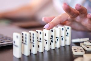 a hand about to knock over a domino
