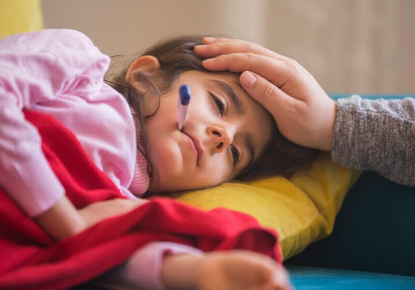 Mother checking on sick daughter laying in bed